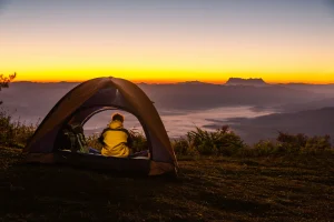 young man sitting tent with looking mountain landscape winter